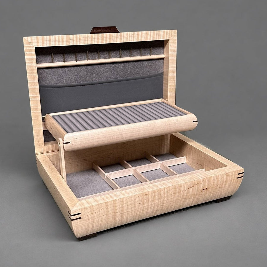 Self-rising tray of a curly maple jewelry box filled with grey velvet ring rolls